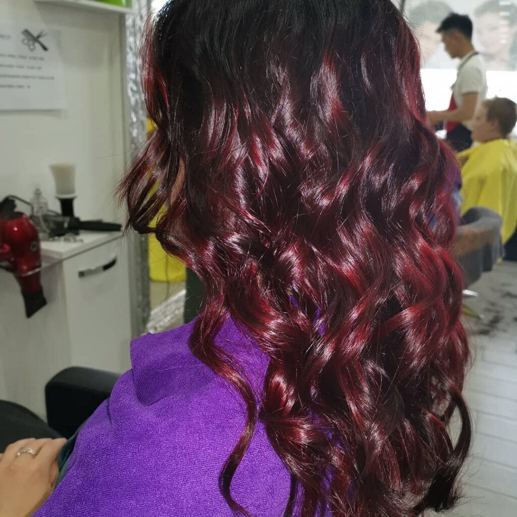 Balayage rosso mogano su capelli scuri e ricci